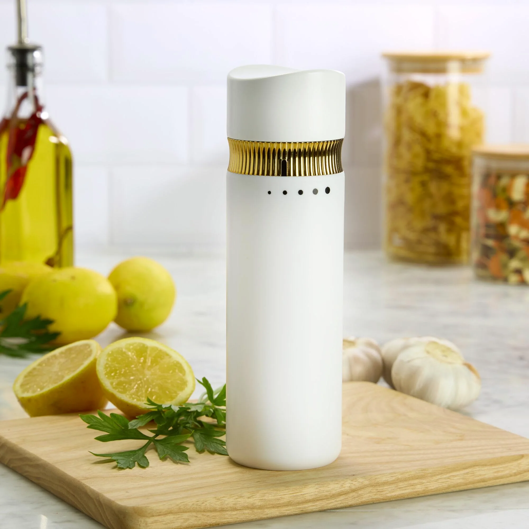 The Kamenstein 8-inch manual mill in white and gold on a cutting board, the five grind dots below its ribbed collar.