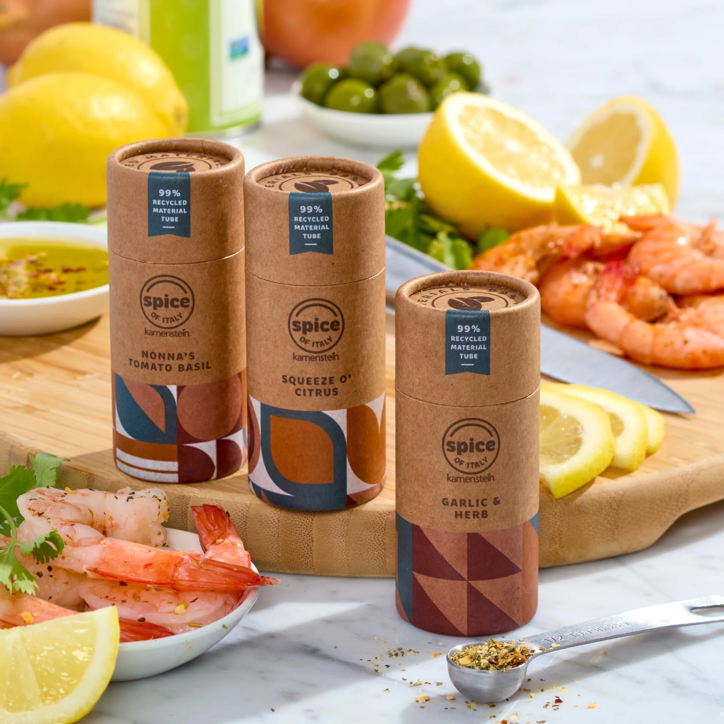 Kamenstein spice blends in paper tubes on a cutting board: Nonna's Tomato Basil, Squeeze O' Citrus and Garlic & Herb.
